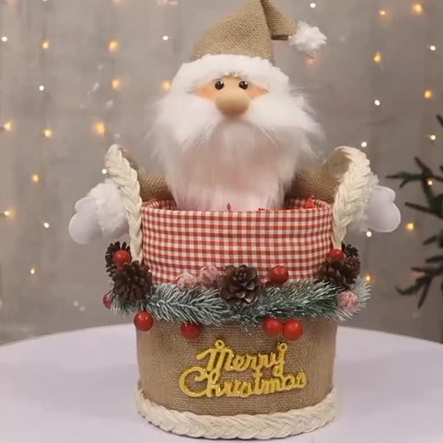 Santa Claus plush figure inside a decorated burlap Christmas gift basket with gold lettering