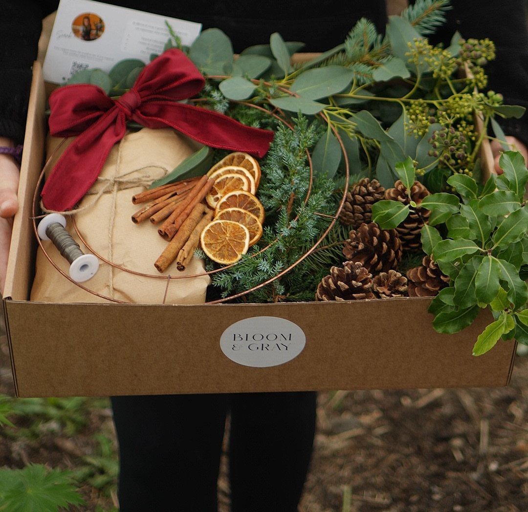 Gift box with cinnamon sticks, dried orange slices, pinecones, and festive greenery.
