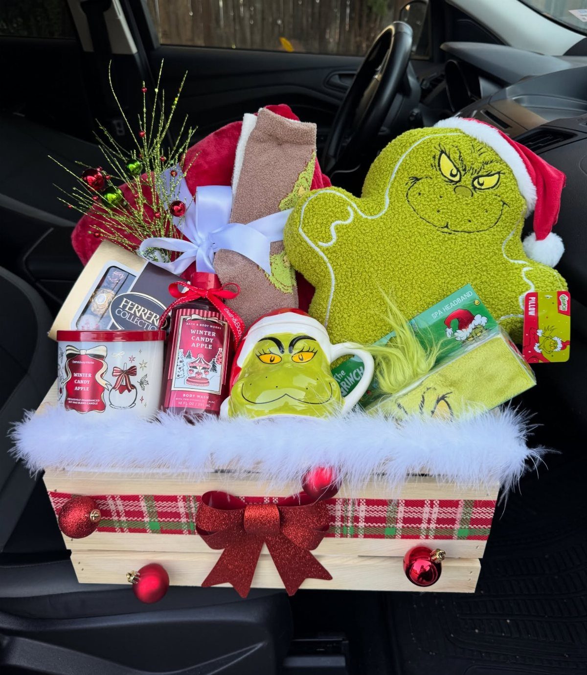 Grinch-themed Christmas gift basket in a wooden crate with plaid ribbon and plush