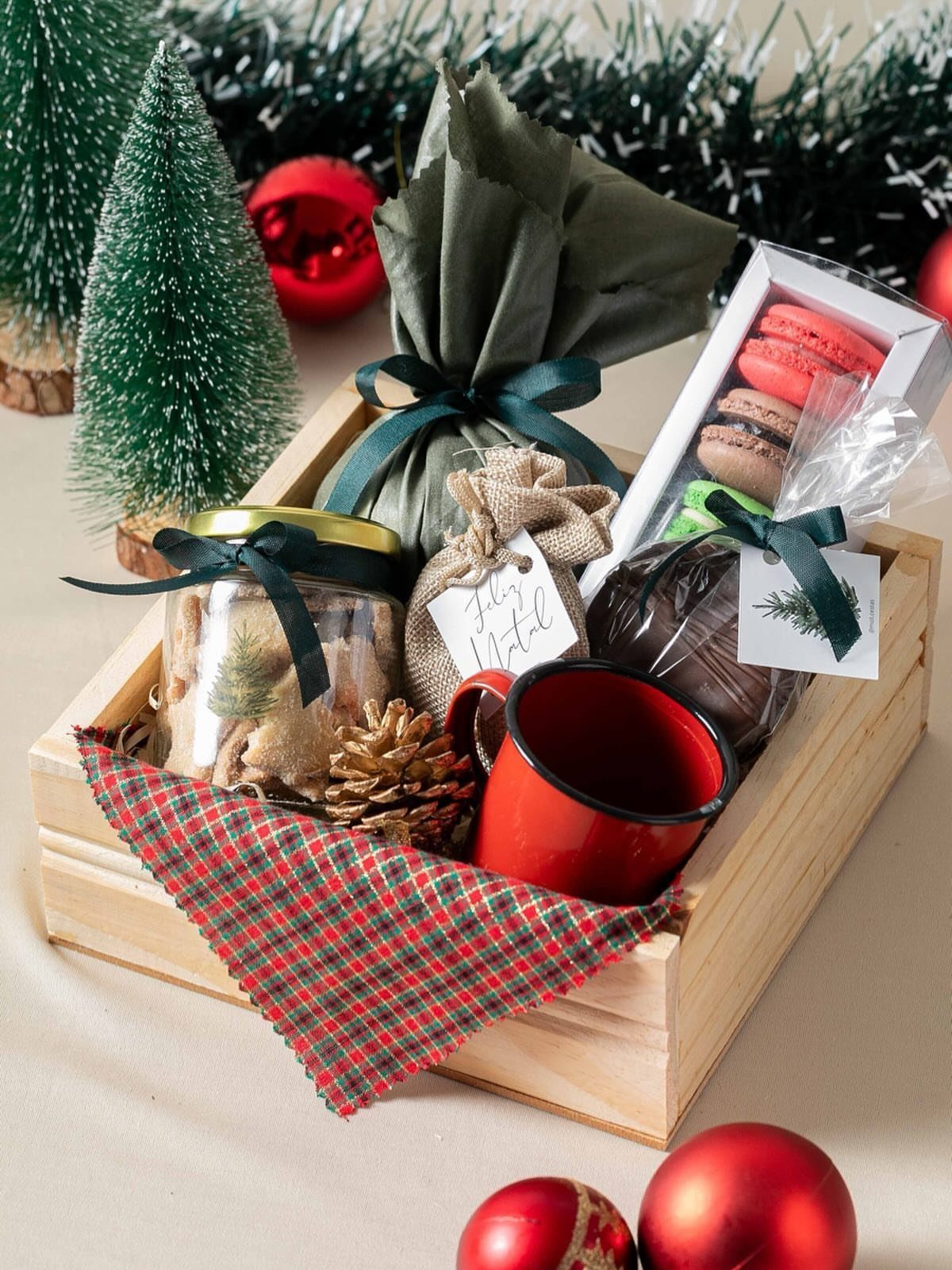 Wooden gift crate with red mug, macarons, and wrapped treats for Christmas