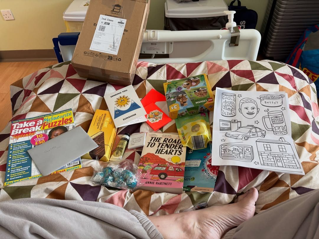 Care package items including books and puzzles on a hospital bed blanket