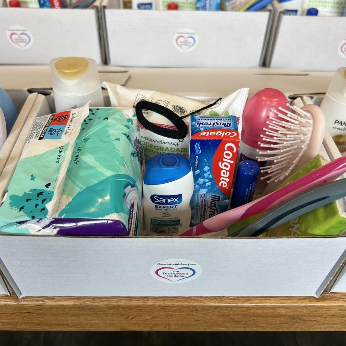 Personal hygiene items including a pink brush and toothpaste in a white box.