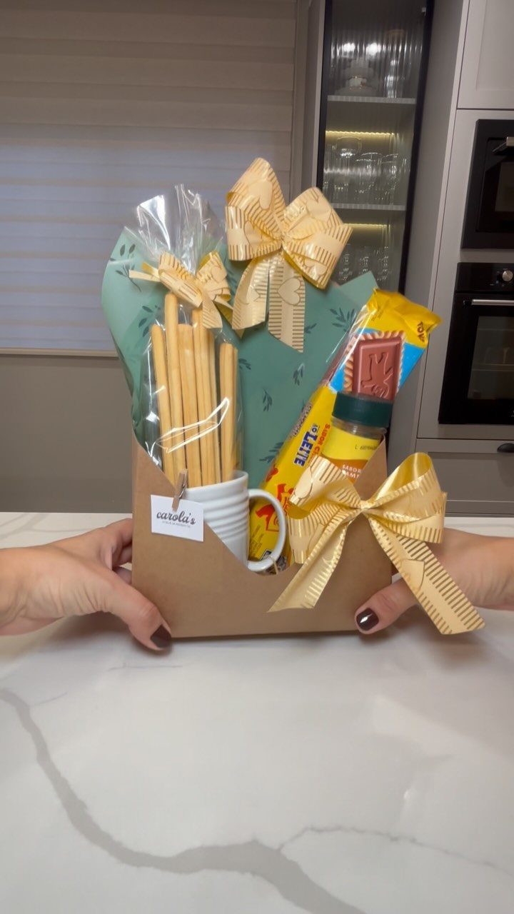 Gift basket in a brown box wrapped in cellophane with gold ribbons.