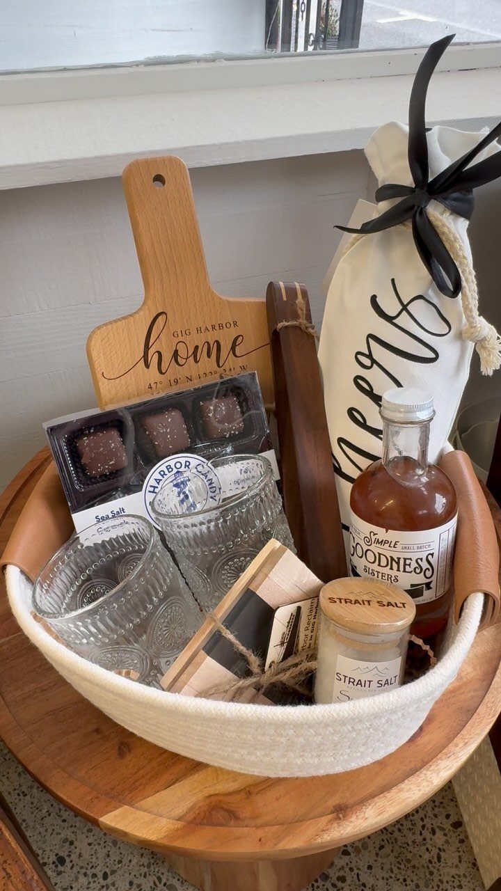 Gift basket filled with a cutting board, chocolates, glassware, and gourmet food items.