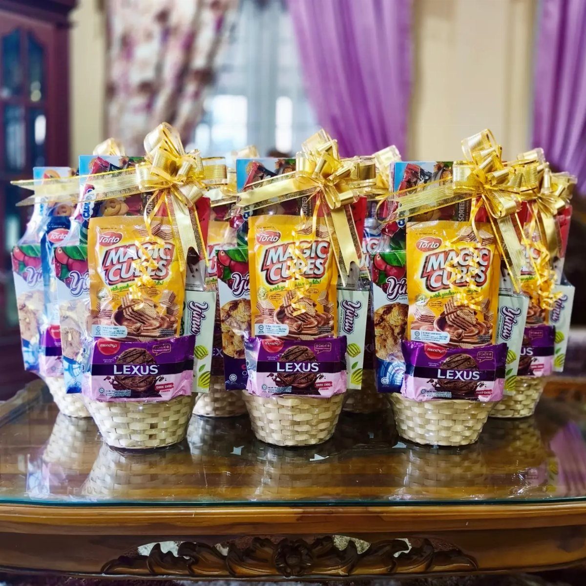 Small white wicker gift baskets wrapped in clear cellophane with gold bows.