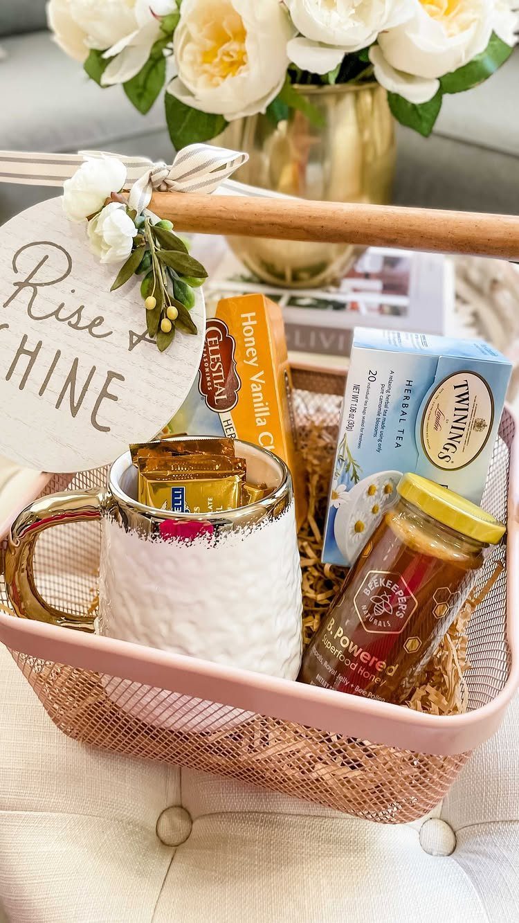Pink wire gift basket containing a white mug, tea, honey, and coffee pods.