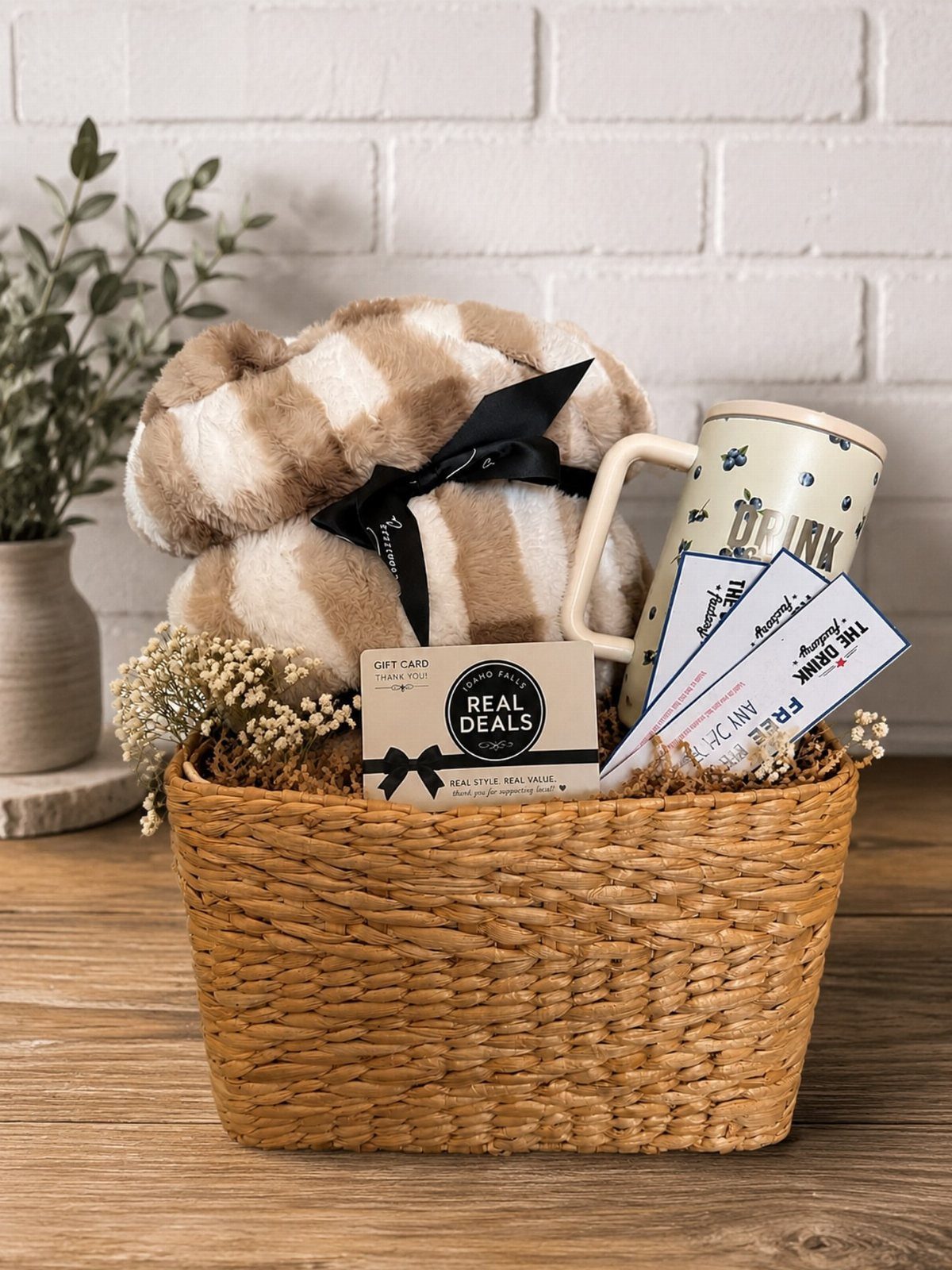 Woven gift basket with a striped plush blanket, white mug, and gift vouchers.