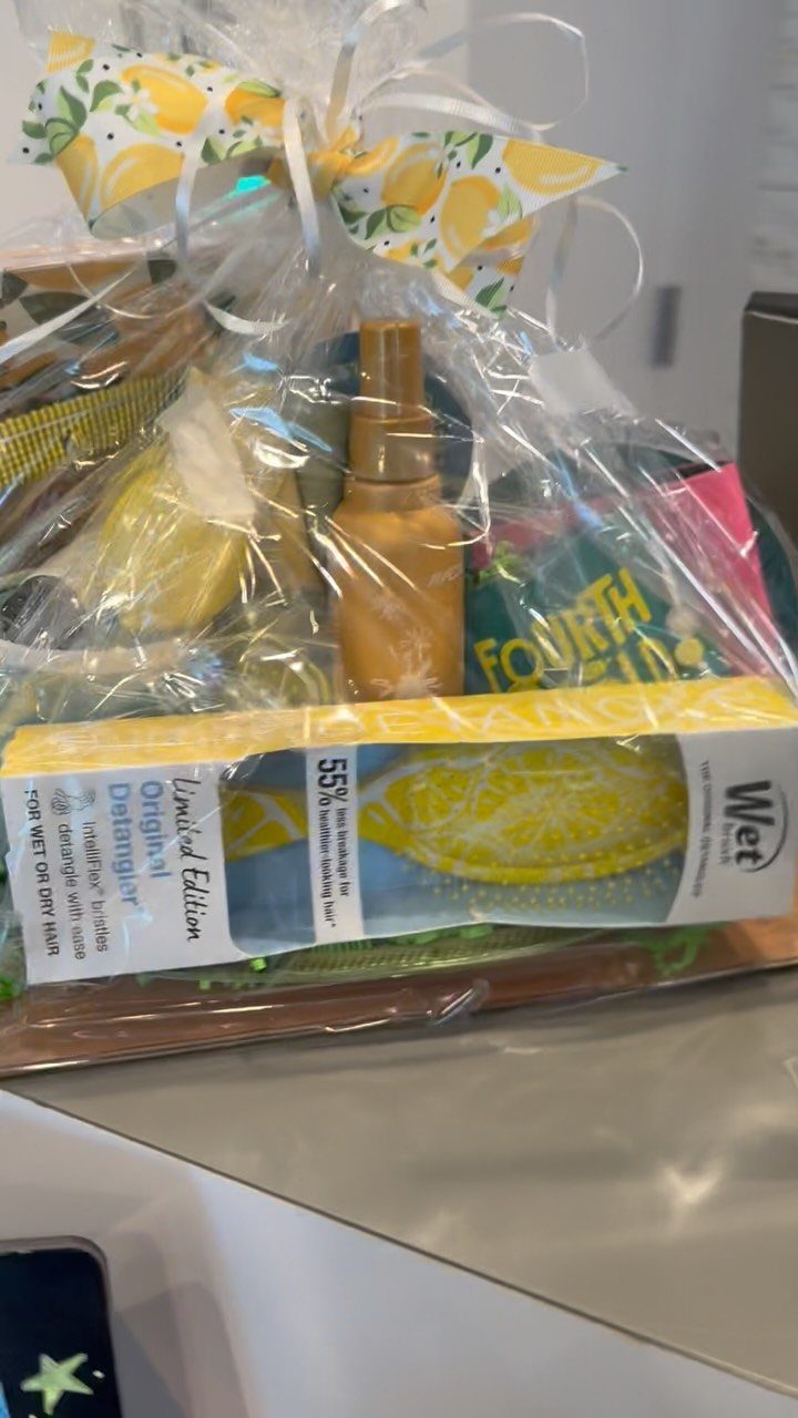Gift basket wrapped in cellophane with a lemon bow and yellow hairbrush.