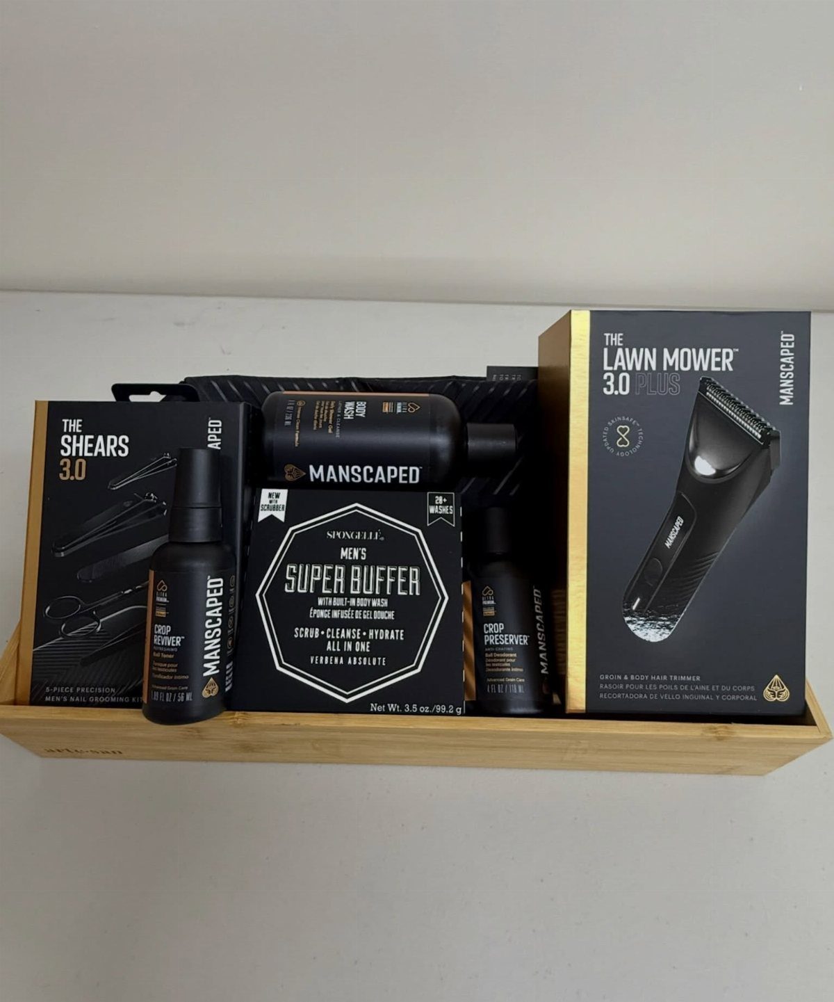 Manscaped grooming kit with trimmer and accessories arranged in a wooden tray.