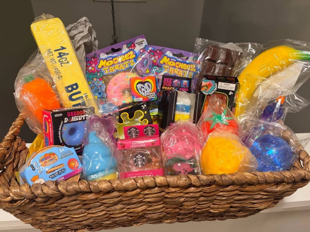 Wicker gift basket filled with colorful squishy toys and packaged candy treats.
