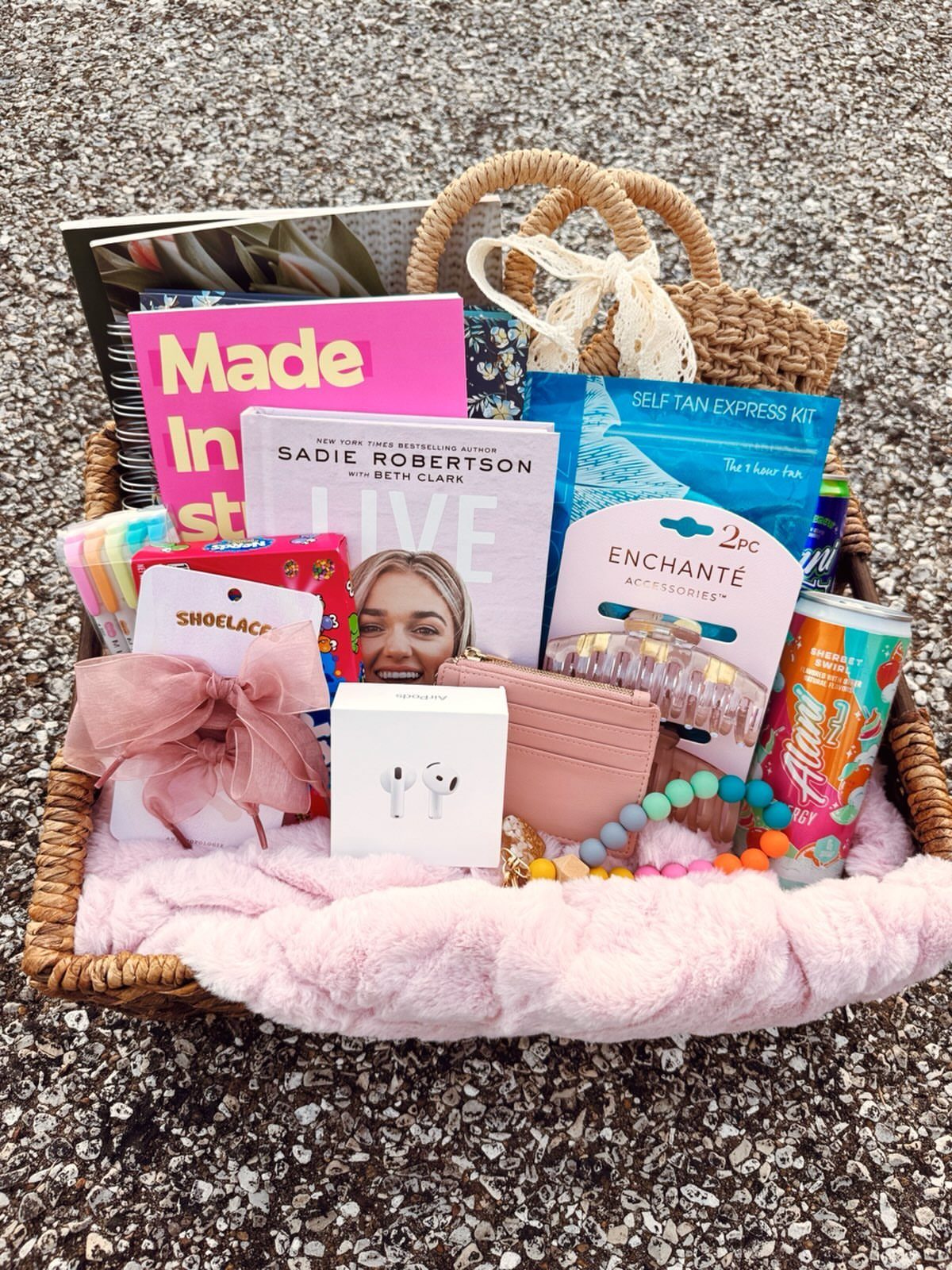 Woven wicker basket filled with pink themed gifts, books, and a fuzzy blanket.