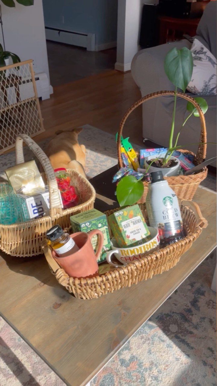 Three wicker gift baskets filled with plants and treats on a wooden table.