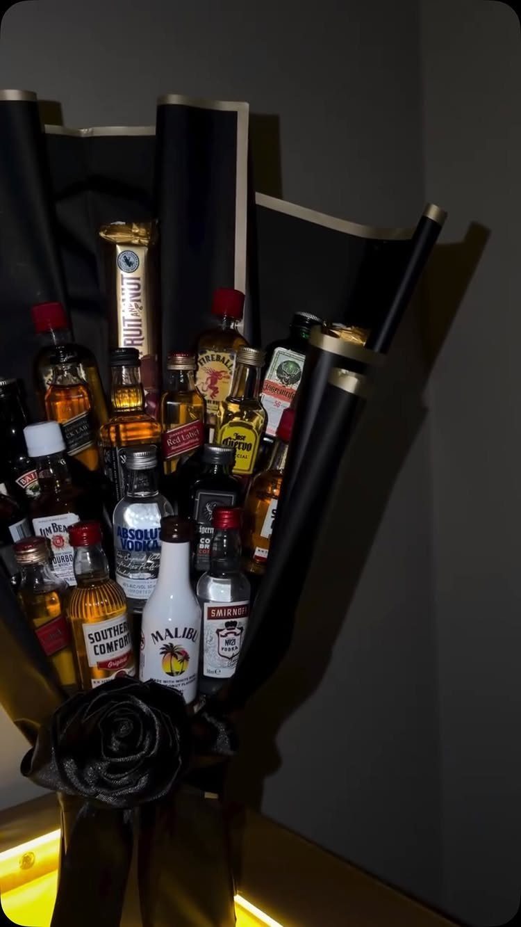 Miniature liquor bottles arranged as a bouquet wrapped in black and gold paper.