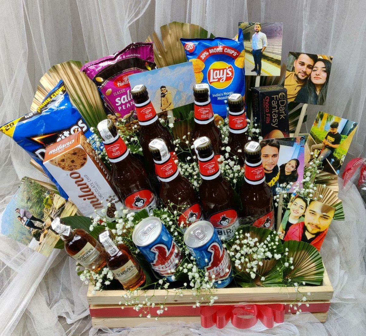 Wooden gift crate with beer bottles, snacks, photos, and white flowers.