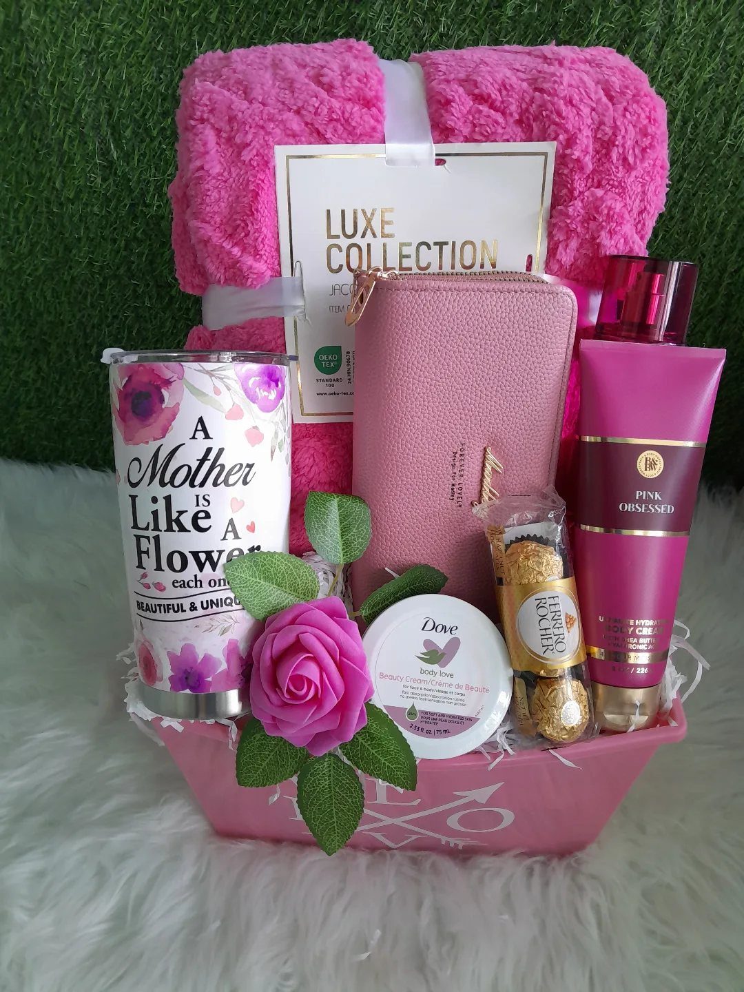 Pink gift basket with towel, wallet, lotion, floral tumbler, and chocolates for mother.