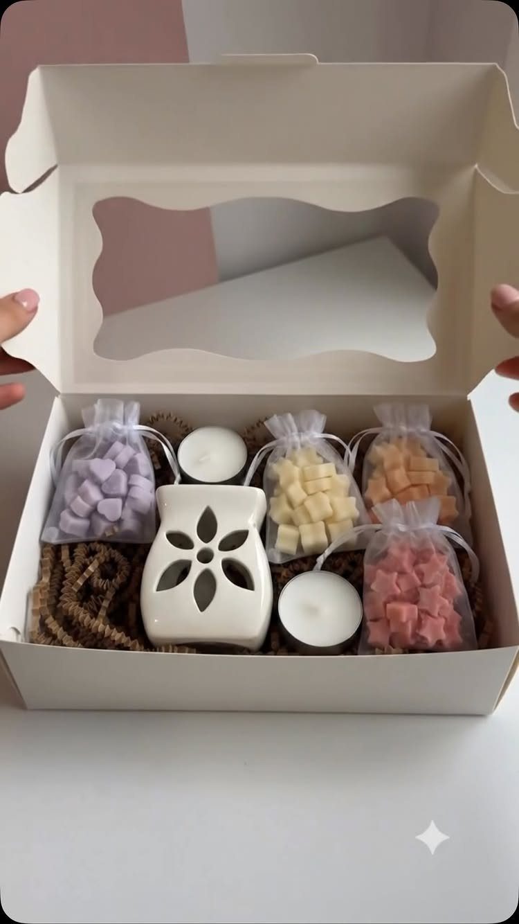 White gift box containing a ceramic wax warmer, tea lights, and colorful wax melts.