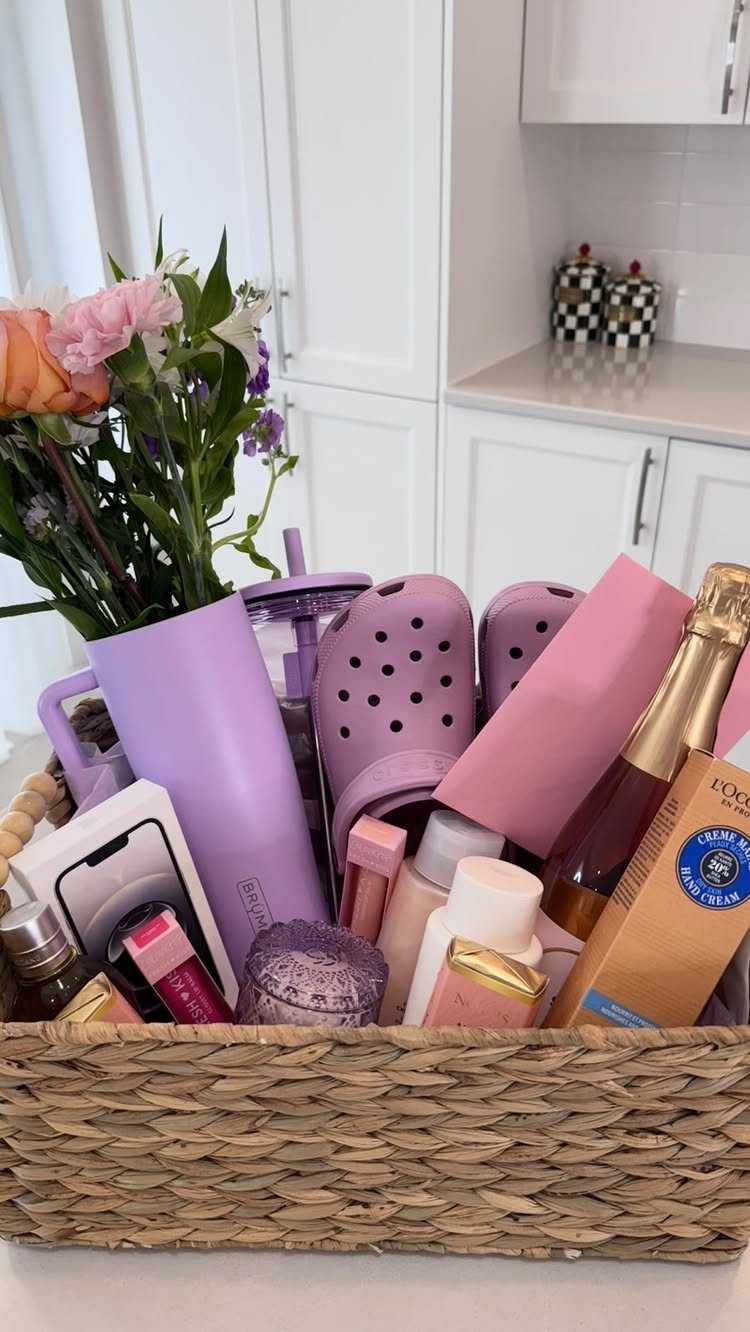 Woven gift basket filled with purple clogs, a tumbler, flowers, and beauty products.