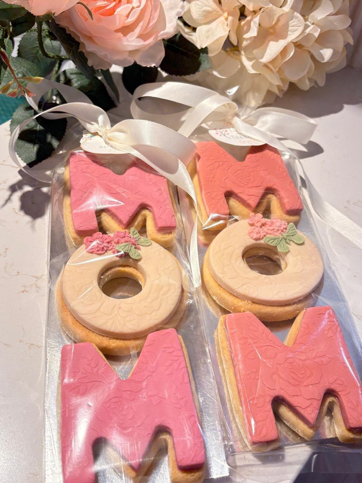 MOM shaped sugar cookies with pink icing in ribbon-tied clear gift bags.
