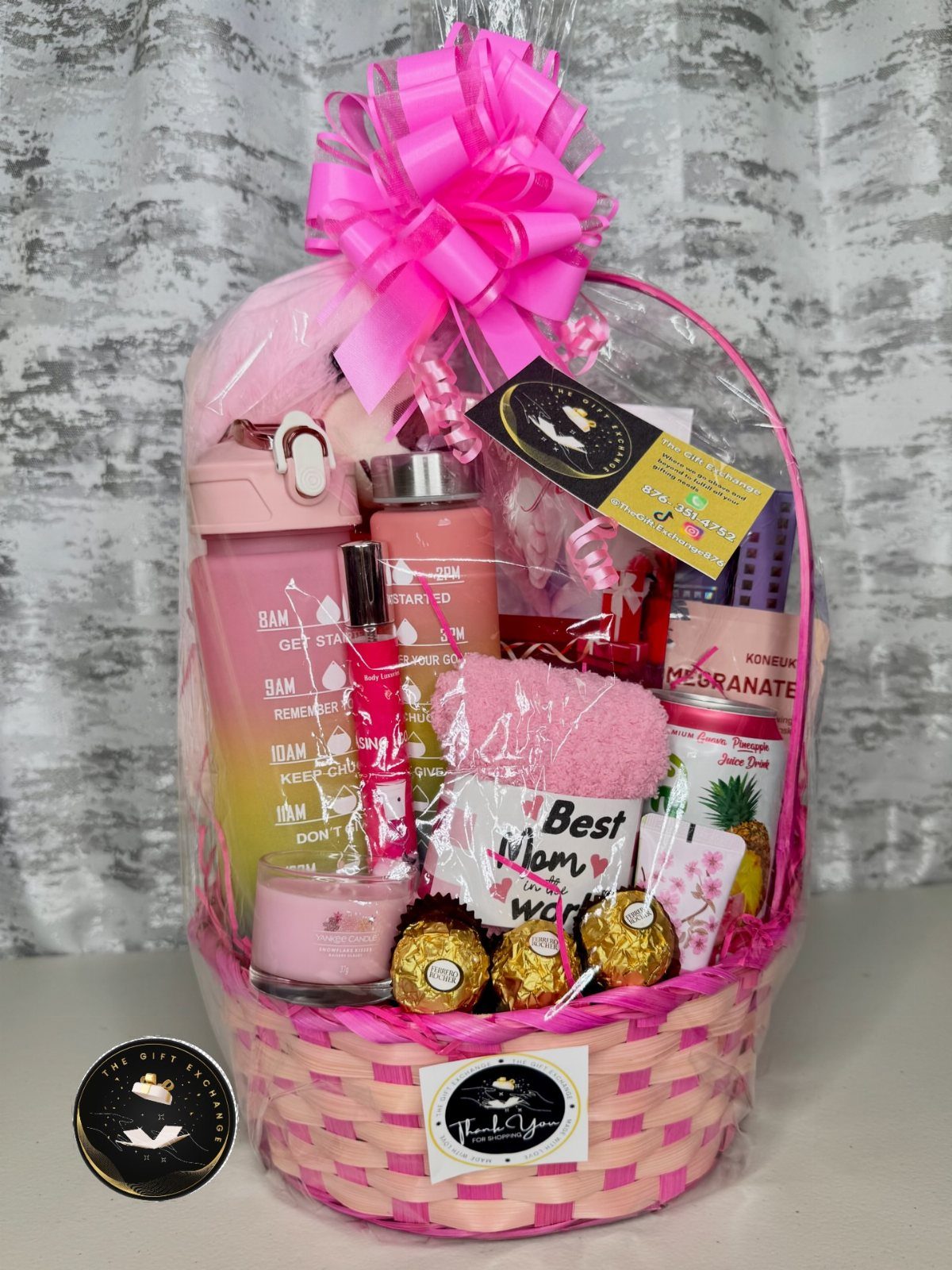 Pink and white gift basket filled with beauty products, a mug, and chocolates.
