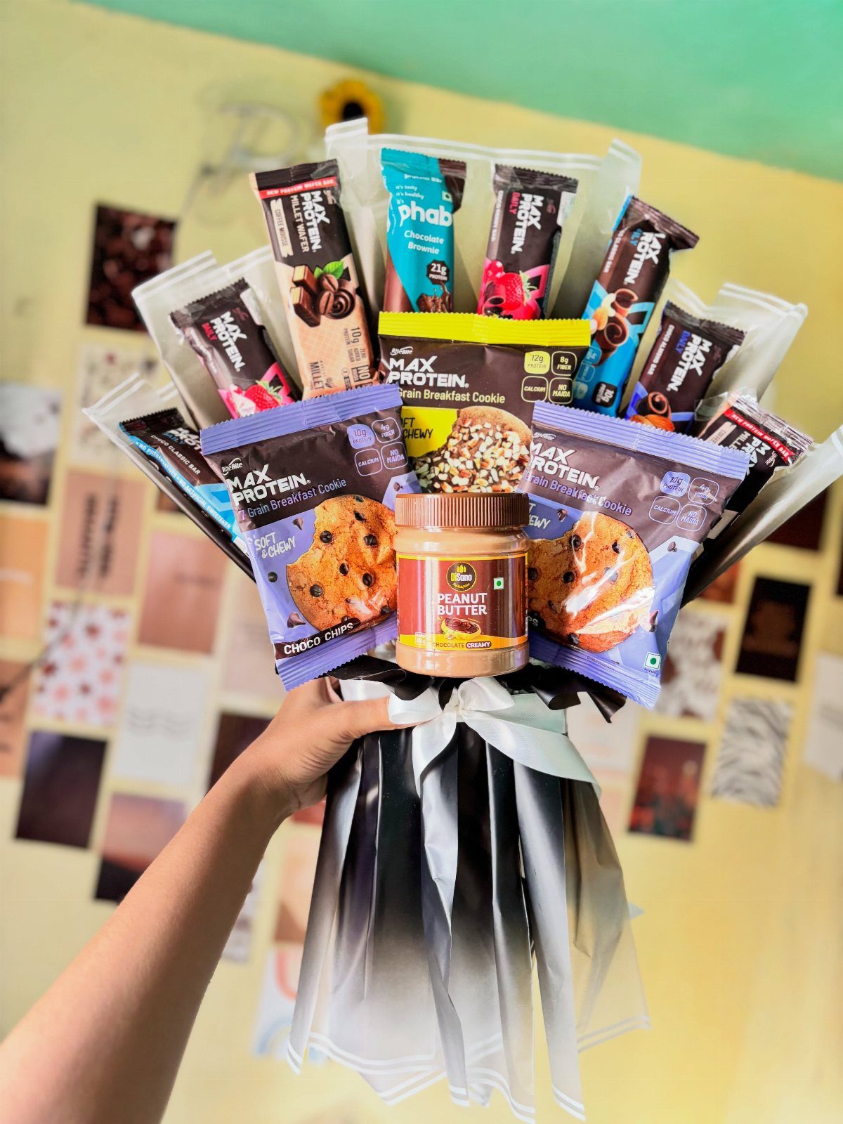 Protein bars and peanut butter arranged as a bouquet held by a hand.