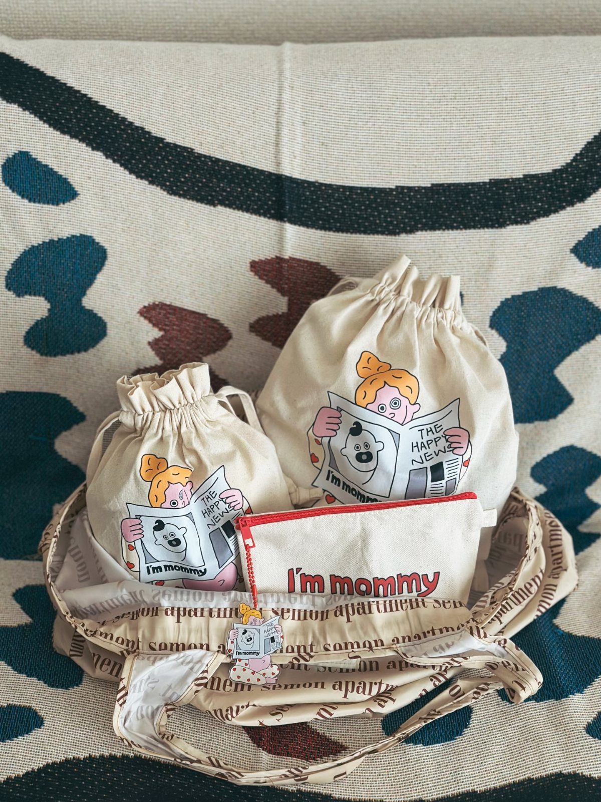 Drawstring pouches and a zippered pouch inside a patterned tote bag on a blanket.