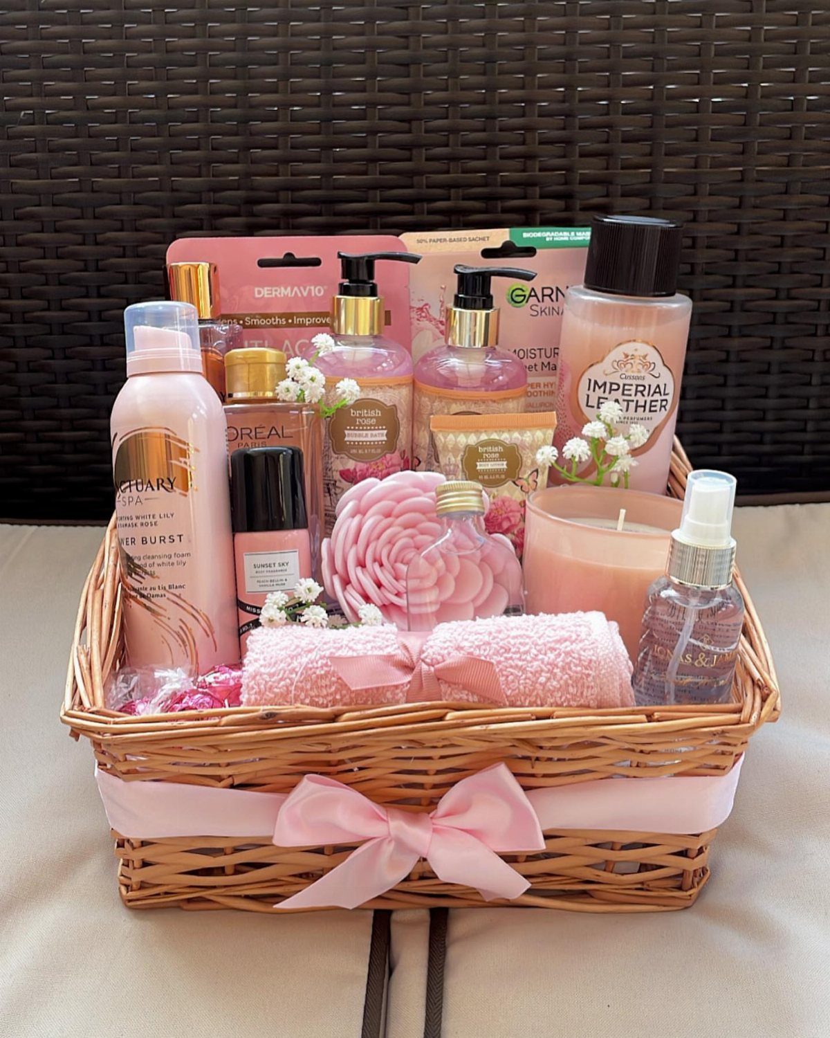Wicker gift basket with pink ribbon containing lotions, soaps, and beauty products.