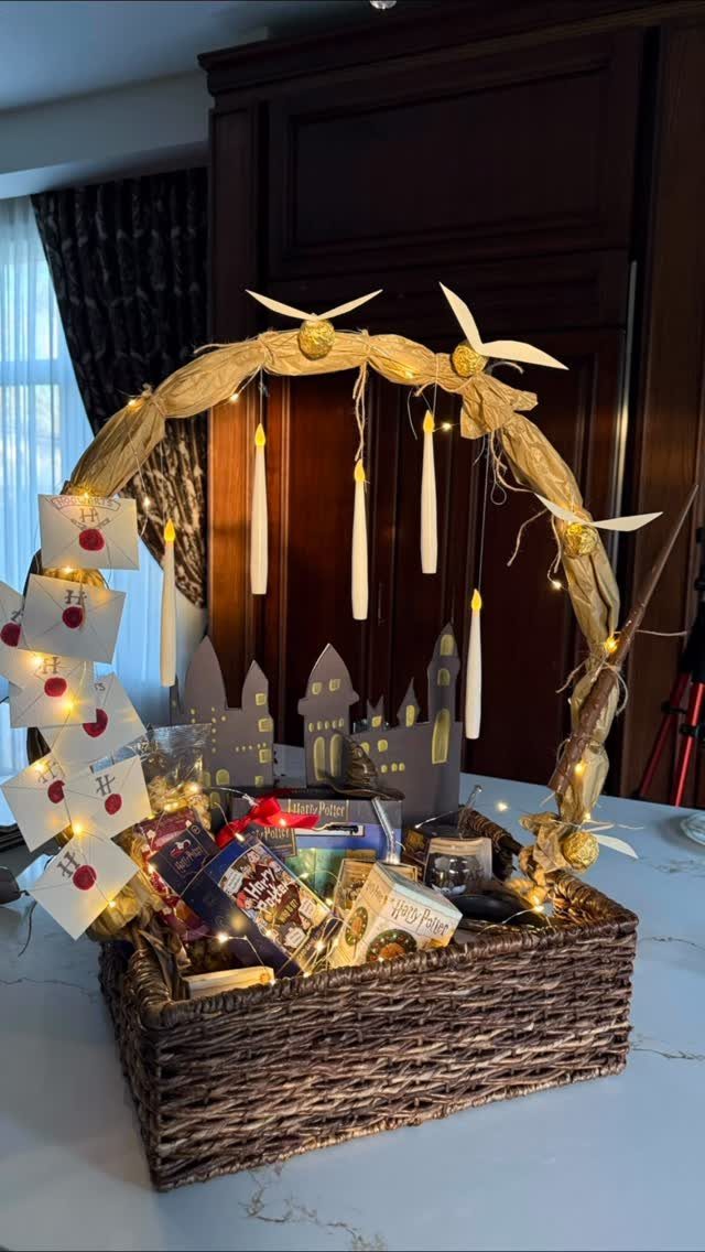 Woven gift basket with snacks, fairy lights, and a decorative candle arch handle.