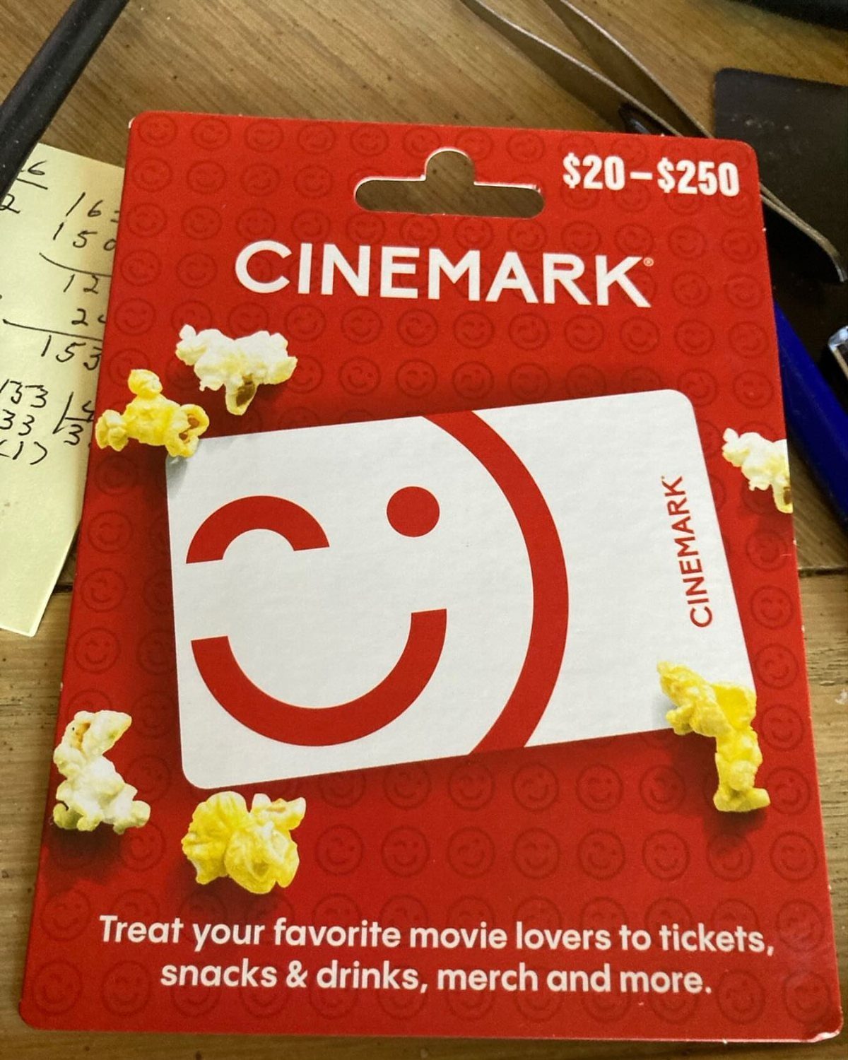 Cinemark gift card with scattered popcorn on a wooden table surface.