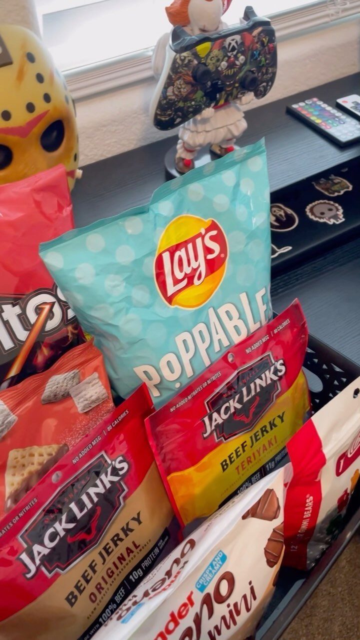 Snack bags including beef jerky and chips arranged in a black plastic basket.