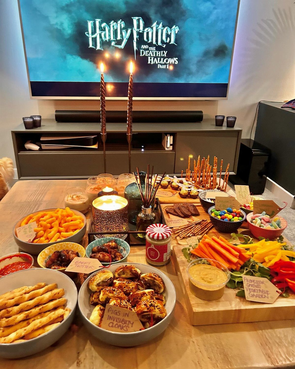 Various snacks in bowls and platters on a table before a movie screen.