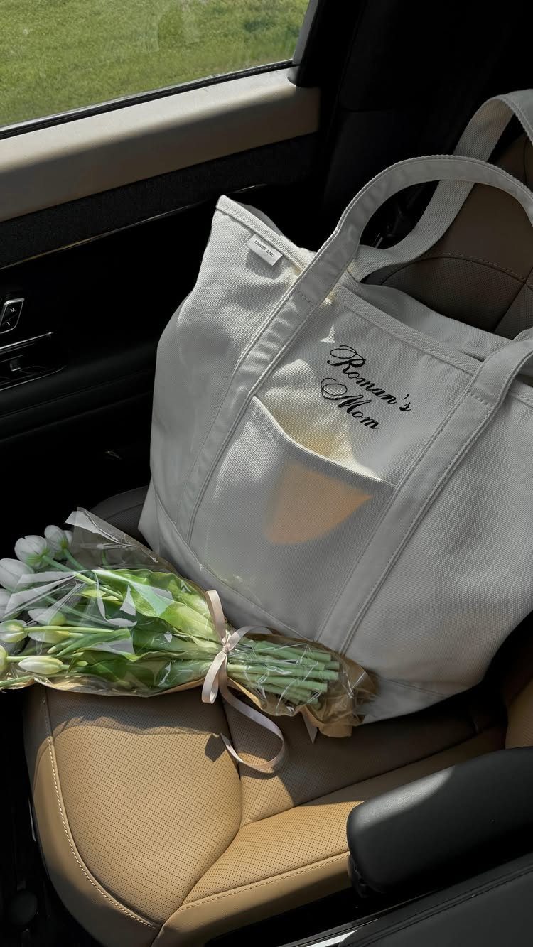 White canvas tote bag and white tulips on a tan car seat