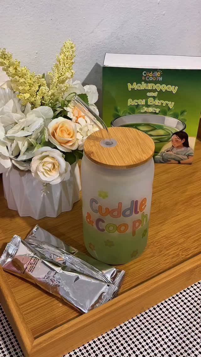 Care package with a green tumbler, juice box, and white roses on a tray.