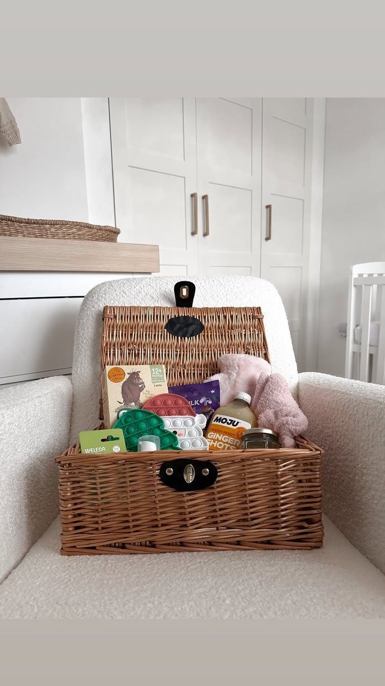 Wicker hamper filled with care package items resting on a white armchair.