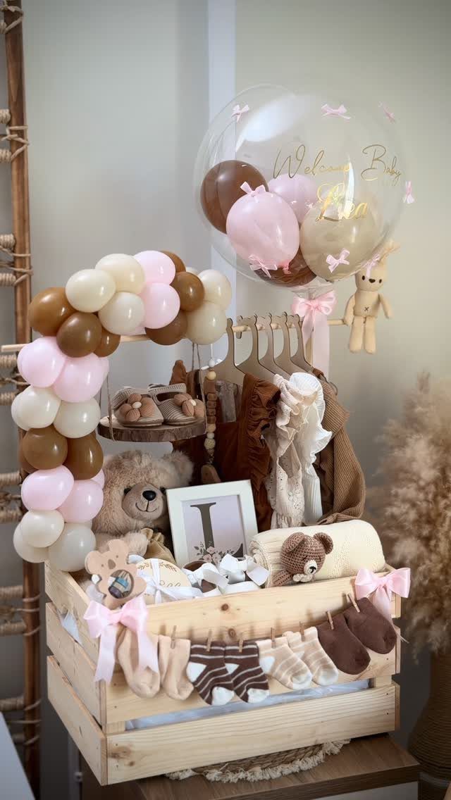 Baby gift basket in a wooden crate with balloons and baby clothes