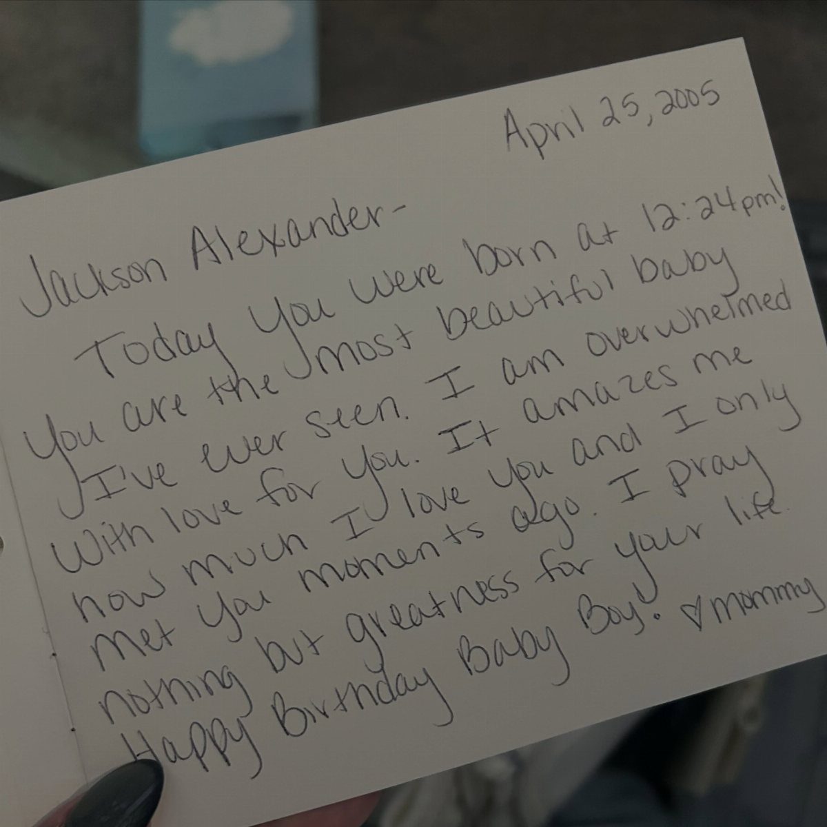 Handwritten note on a white card addressed to a newborn baby boy.