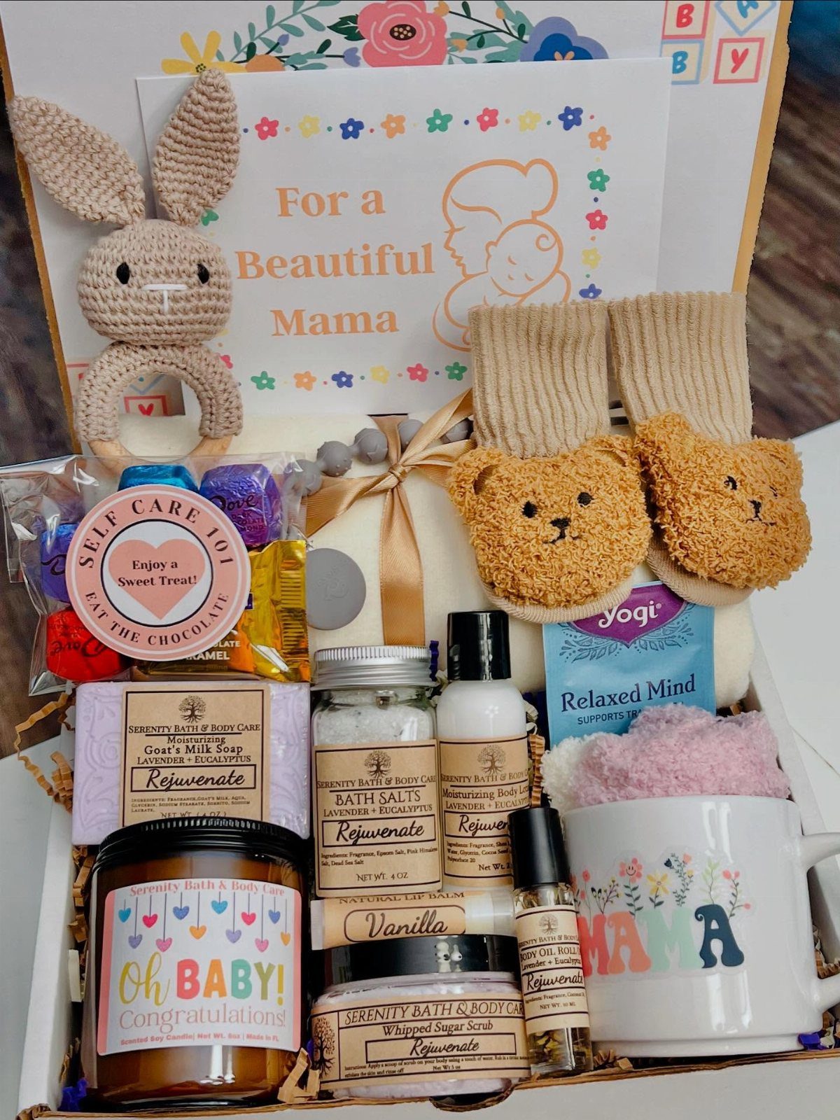 Gift basket for a new mother containing baby toys, slippers, and spa products.