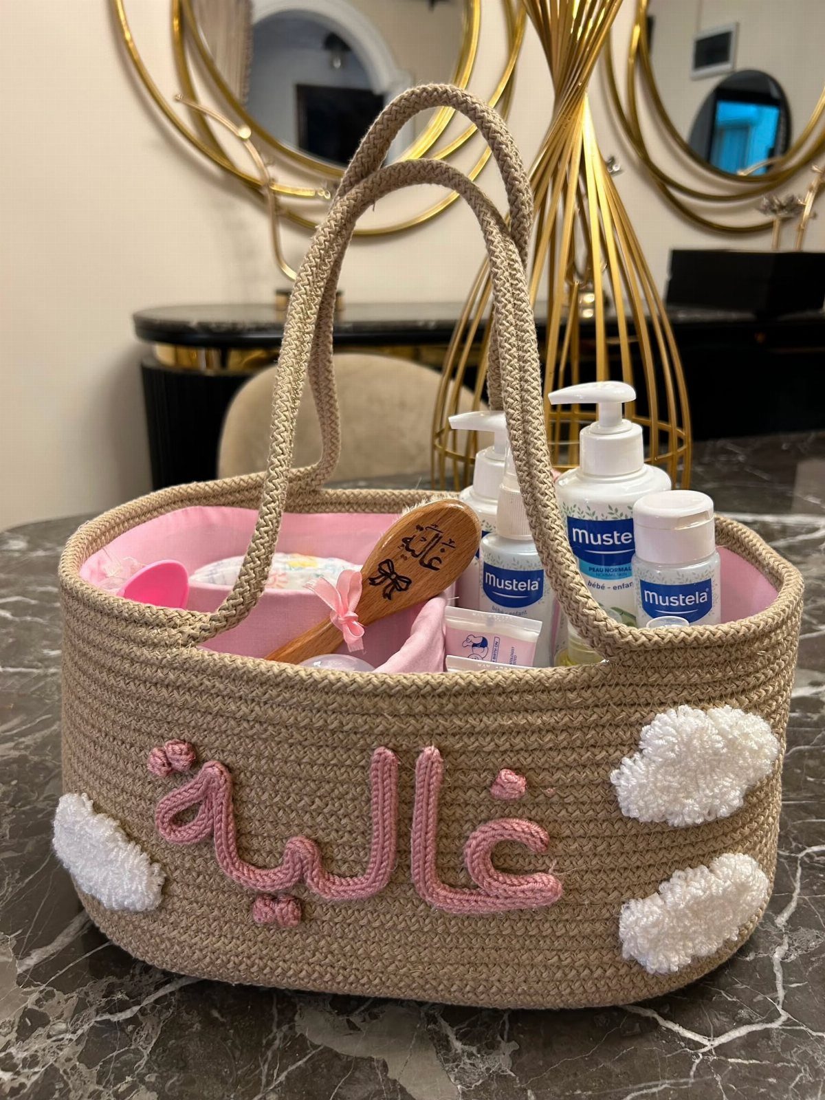 Crocheted baby gift basket with Mustela skincare products and a wooden hairbrush.