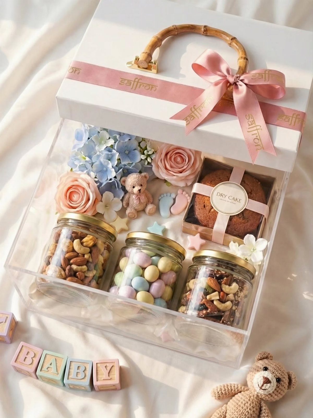 Gourmet food gift box with nuts, candies, cake, and baby-themed decorations.