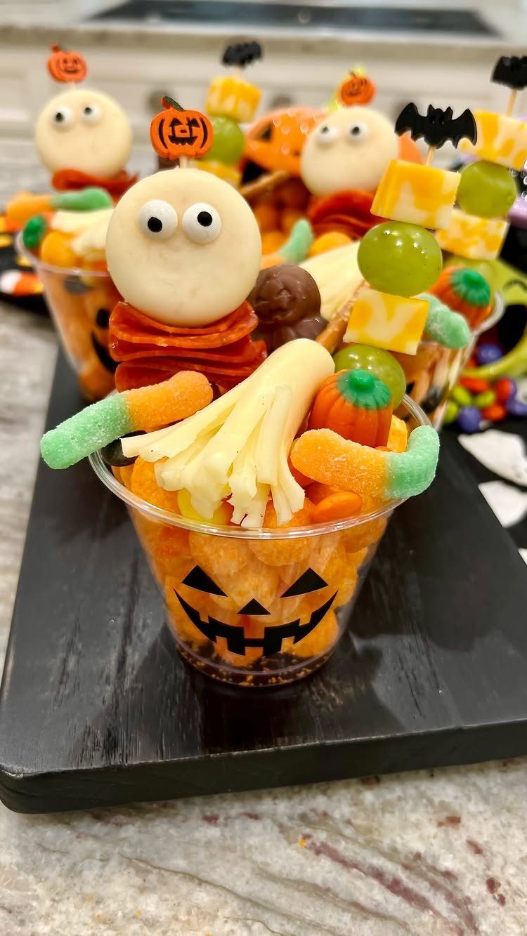 Halloween snack cups with cake pop ghosts, grapes, and cheese on black tray
