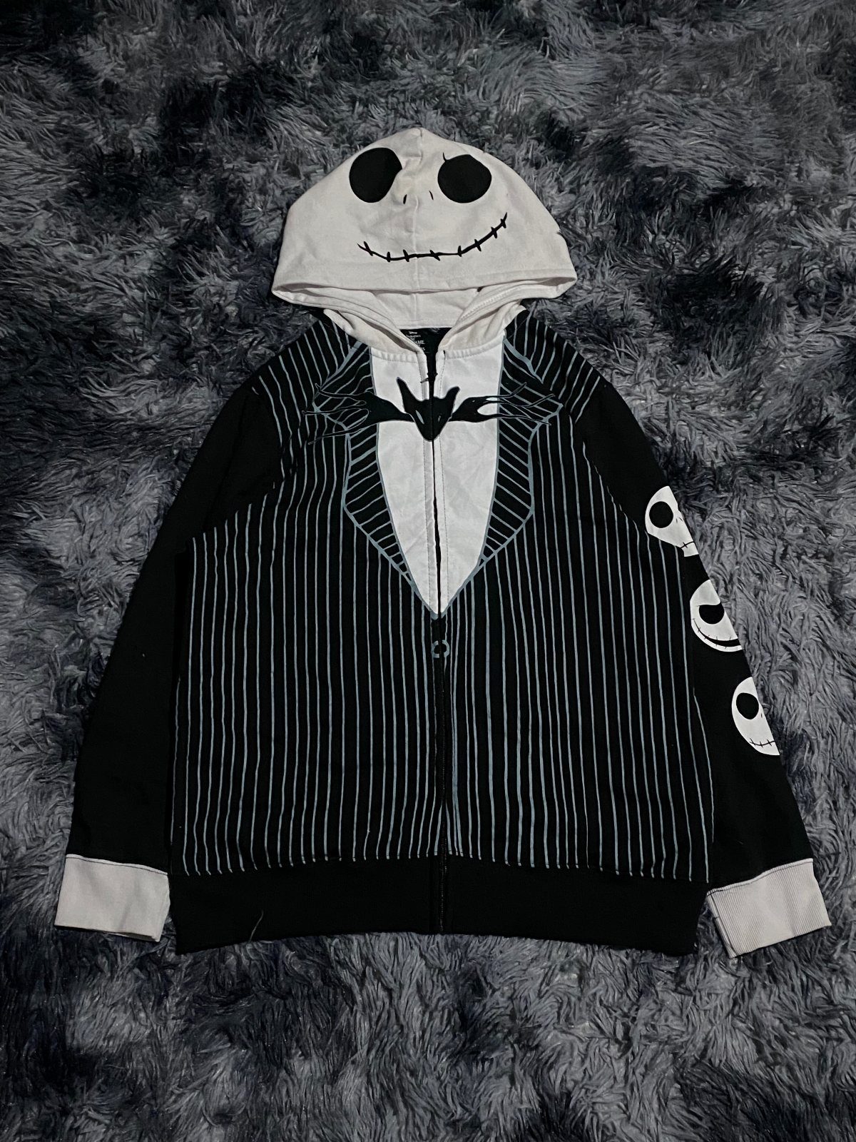 Jack Skellington pinstripe suit hoodie laid on a grey fluffy background