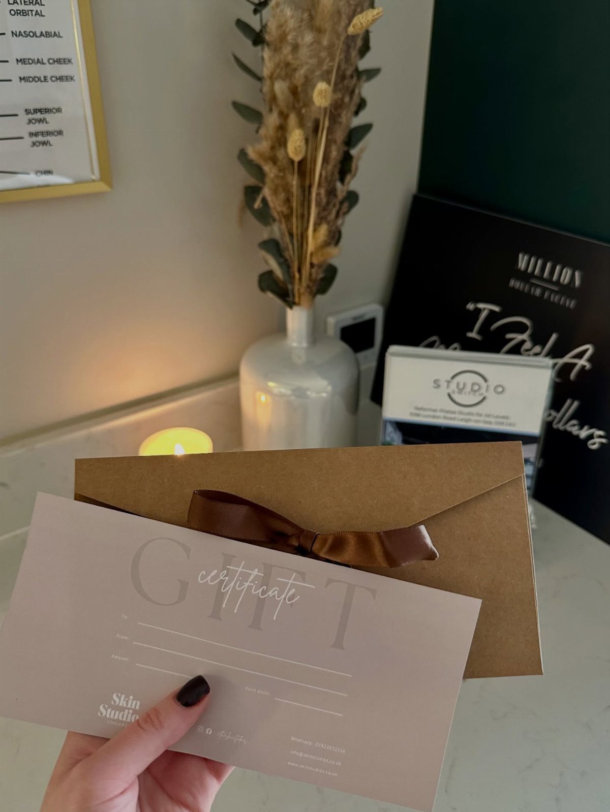 Gift certificate for a skin studio held in front of a brown envelope.