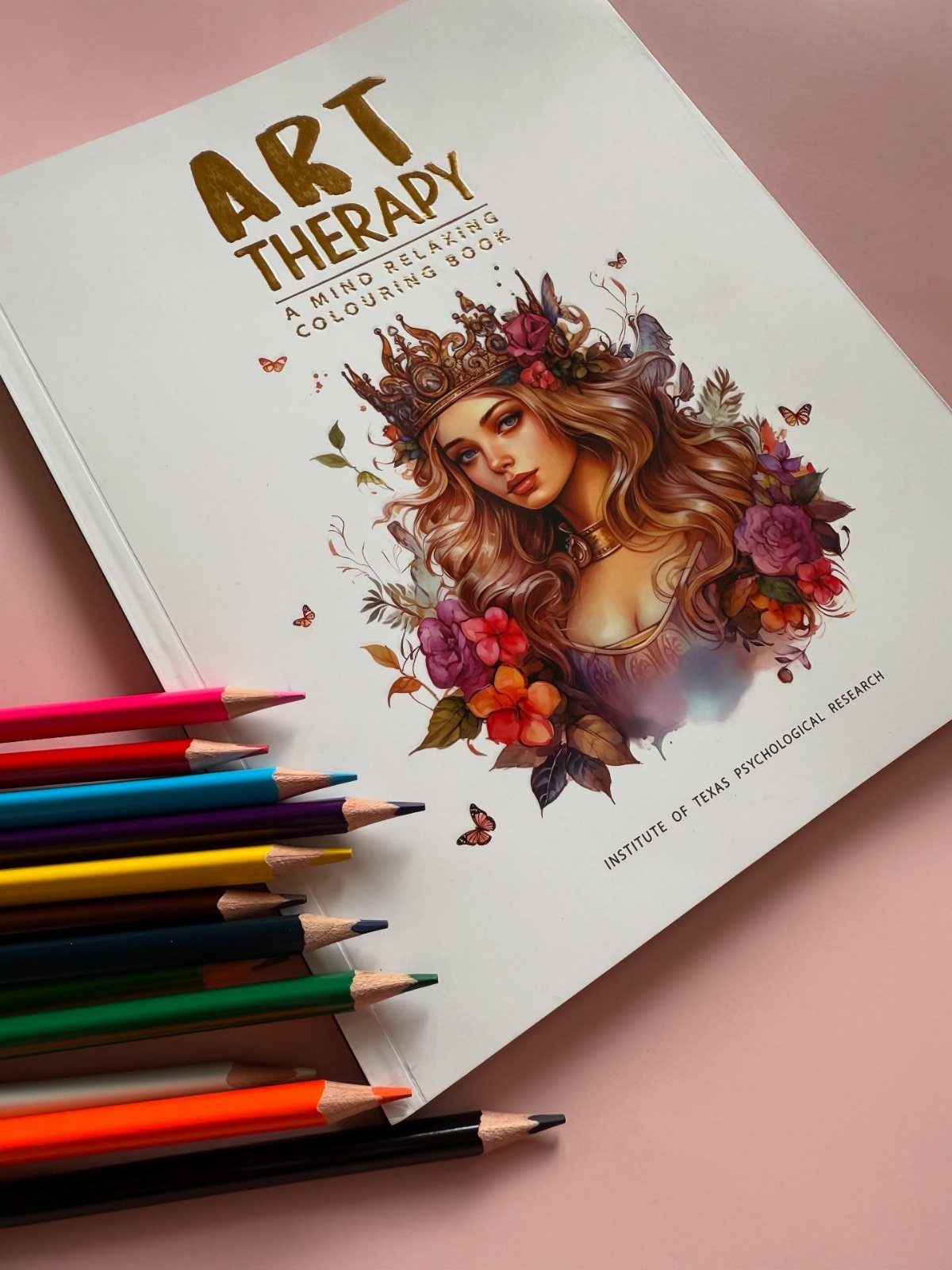 Art therapy coloring book and colorful pencils on a pink background