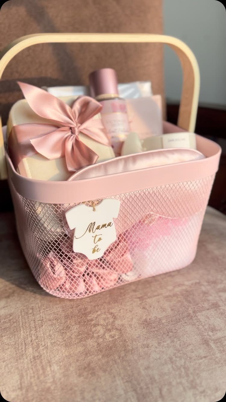 Pink mesh gift basket filled with beauty products and a Mama to be tag.