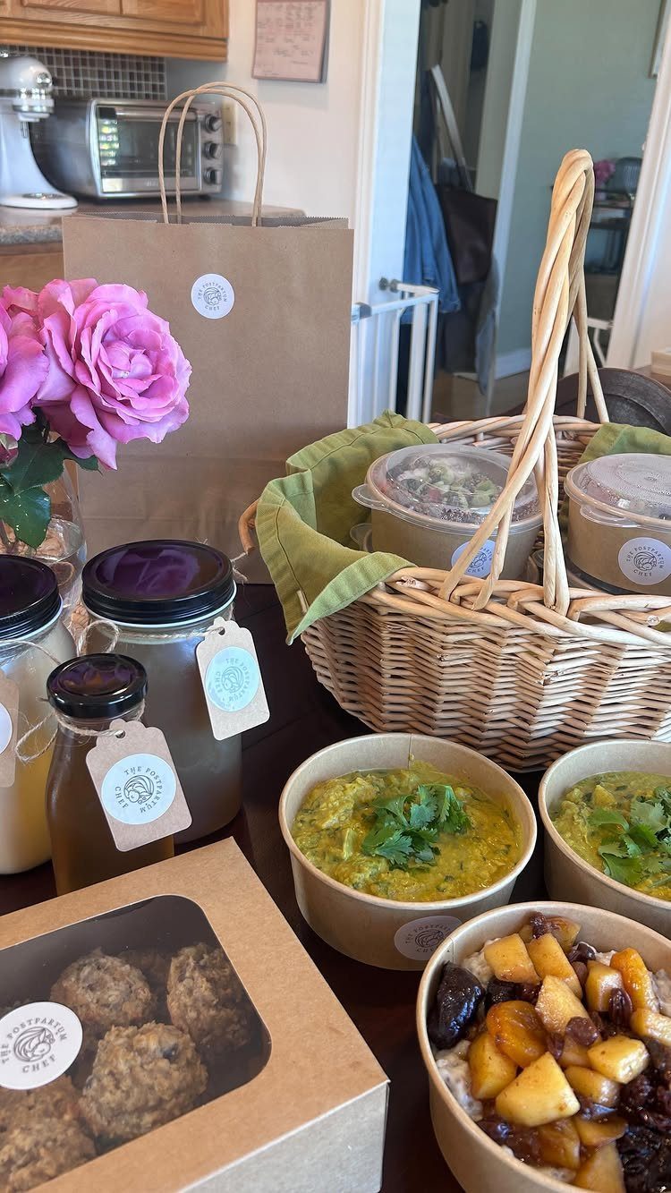 Wicker basket and meal containers with energy bites and pink roses on table