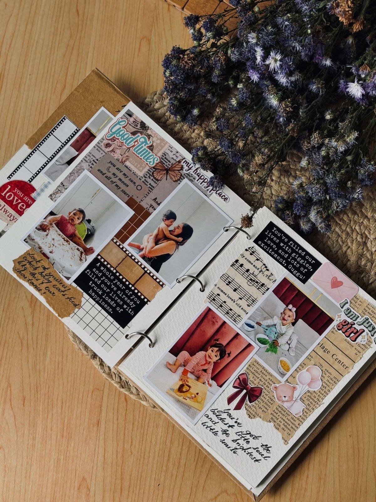 Open baby memory book with photos, handwritten notes, and dried purple flowers.
