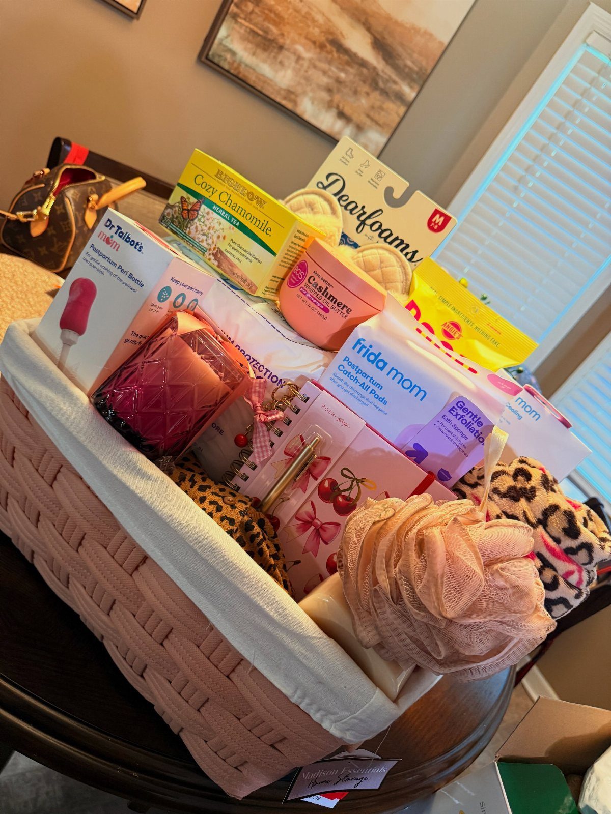 Woven gift basket containing postpartum care products, tea, and leopard print cozy socks.