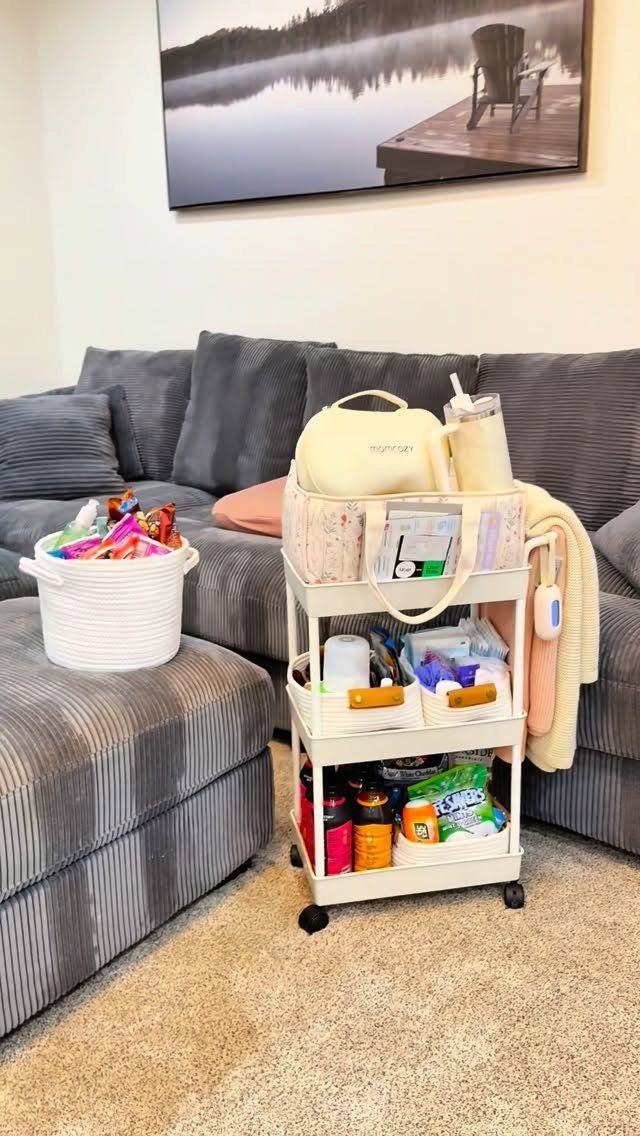 White rolling cart filled with postpartum care supplies and snacks next to a sofa.