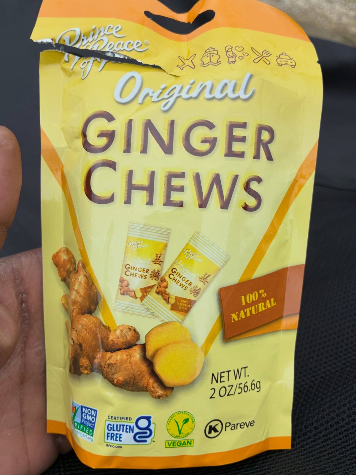 Yellow bag of ginger chews candies held by a person's hand.