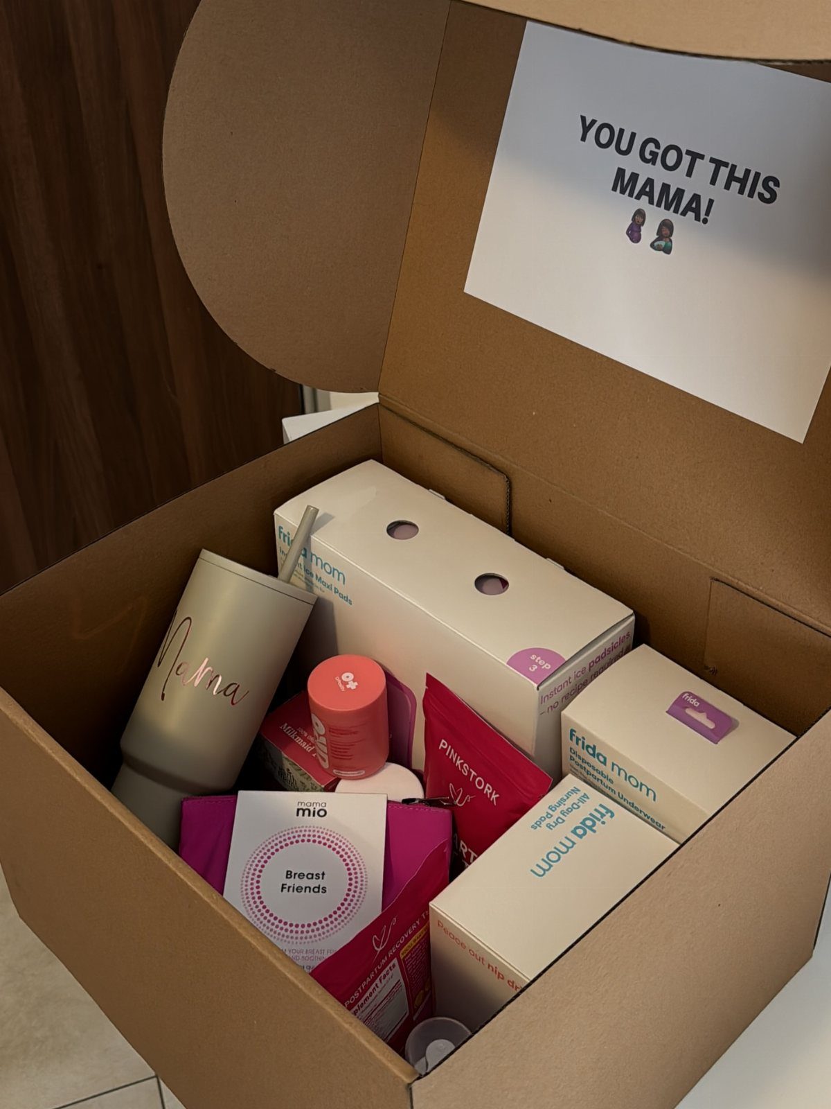 Cardboard care package filled with pregnancy products and a supportive note for mama