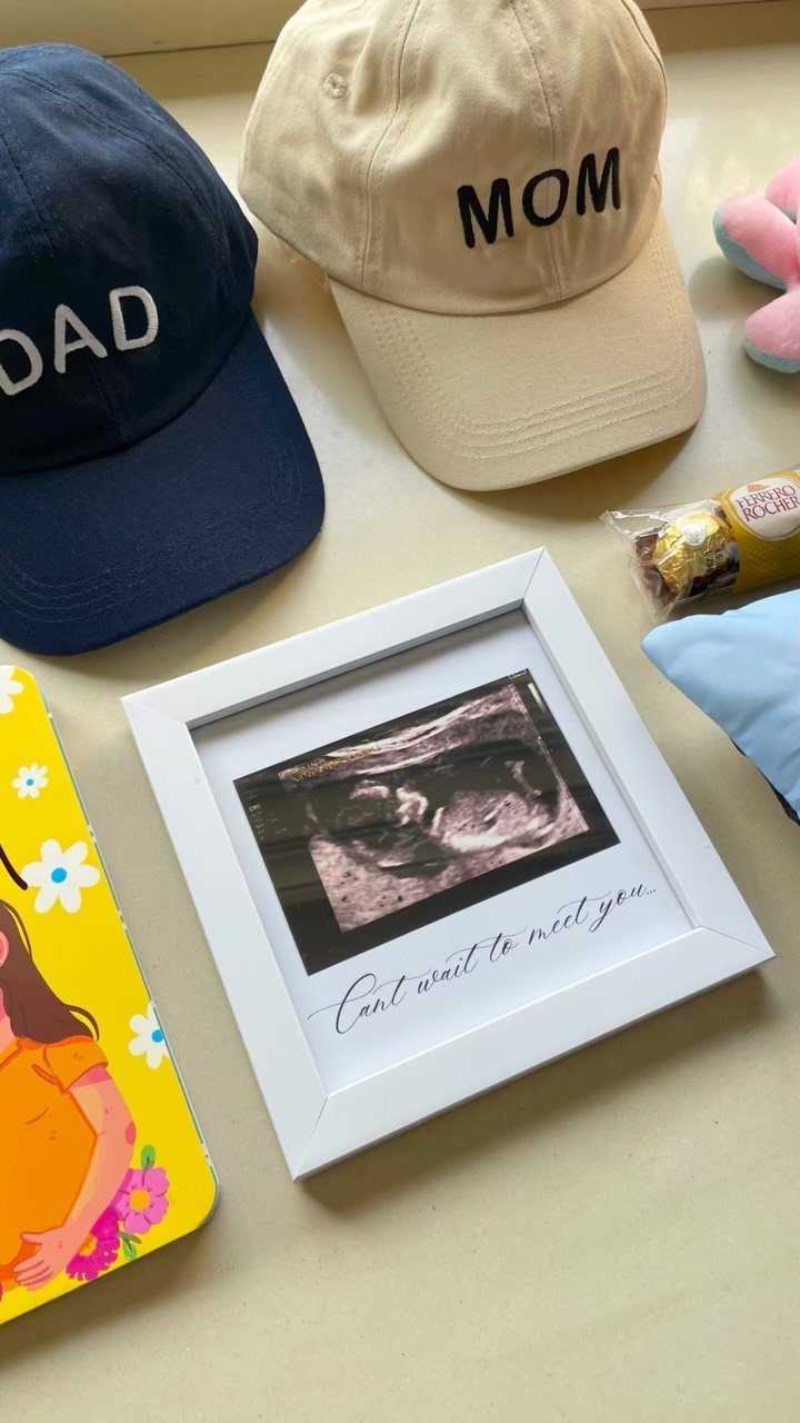 Pregnancy gift items including Mom and Dad caps and a framed ultrasound photo.